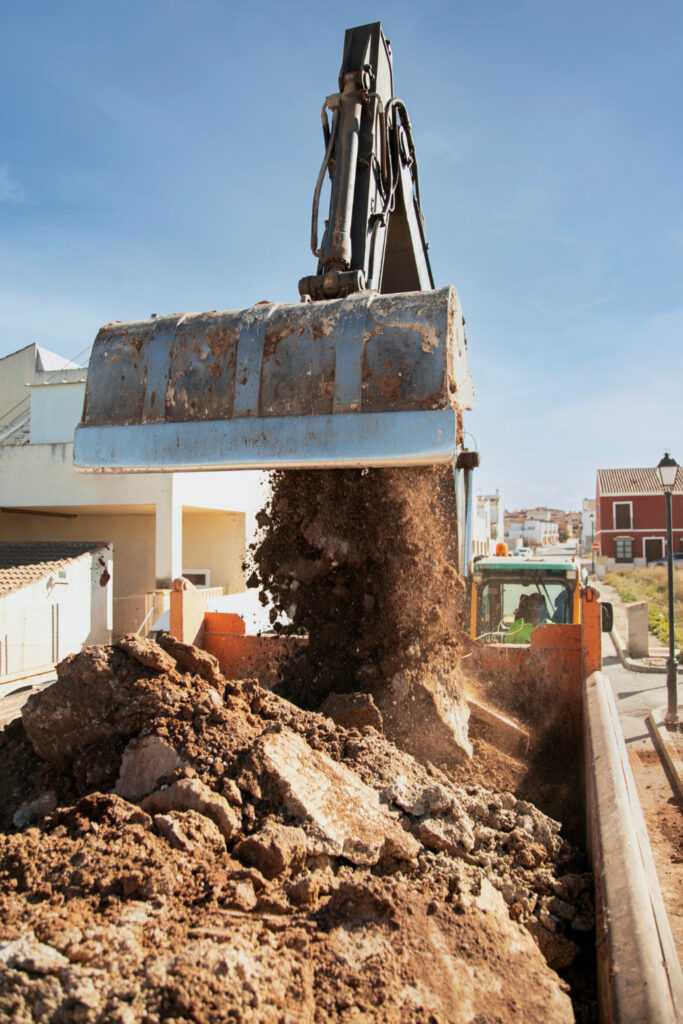 Déchargement de déblais par godet mécanique sur chantier de terrassement à Caen.