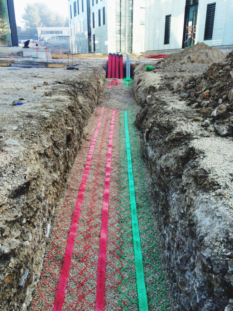 Tranchée technique pour réseaux enterrés sur chantier de génie civil à Caen.