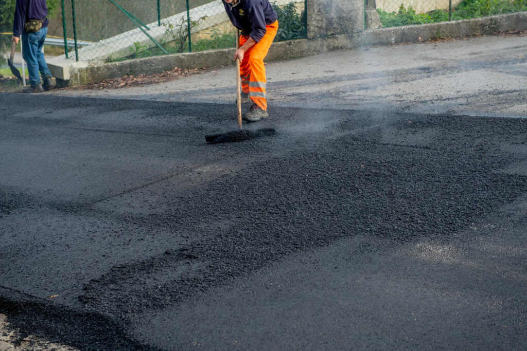 Application manuelle d’enrobé sur chaussée pour travaux de voirie à Caen.